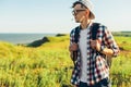 Young man, in glasses and in a cap with a backpack, hiking and enjoying the mountain landscape, adventure man hiking in the desert Royalty Free Stock Photo