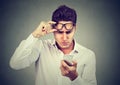 Young man with glasses having trouble seeing cell phone has vision problems. Bad text message. Royalty Free Stock Photo