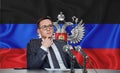 Young man in glasses and a jacket at an international meeting or press conference negotiations, on the background of the flag dnr