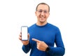 Young man in glasses looking at camera pointing finger at mobile phone isolated on white background Royalty Free Stock Photo