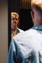 Young man in glasses looks at himself in the mirror and straightens his shirt Royalty Free Stock Photo