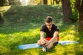 Young man in glasses training yoga outdoors. Sporty guy makes relaxing exercise on a blue yoga mat, in park. Copy space Royalty Free Stock Photo