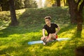 Young man in glasses training yoga outdoors. Sporty guy makes relaxing exercise on a blue yoga mat, in park. Copy space Royalty Free Stock Photo