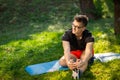 Young man in glasses training yoga outdoors. Sporty guy makes relaxing exercise on a blue yoga mat, in park. Copy space Royalty Free Stock Photo