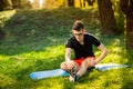 Young man in glasses training yoga outdoors. Sporty guy makes relaxing exercise on a blue yoga mat, in park. Copy space Royalty Free Stock Photo