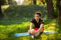 Young man in glasses training yoga outdoors. Sporty guy makes relaxing exercise on a blue yoga mat, in park. Copy space Royalty Free Stock Photo