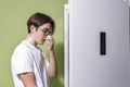 Man feeling bad smell from fridge in kitchen