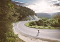 Young man riding on a longboard on the road.