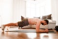 Young man go in for sport at home. Full size picture of t-shirtless guy sportsman stand in plank position alone in room