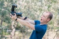 Young male guy got scared of the DSLR camera holding it in his hands on summer day. Funny picture of beginners in career of photog