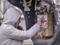 A young man in a gray jacket with a hood is calling from an old payphone on the street Royalty Free Stock Photo