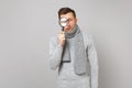 Young man in gray sweater, scarf holding, looking behing magnifying glass isolated on grey wall background. Healthy Royalty Free Stock Photo