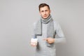 Young man in gray sweater, scarf pointing index finger on daily pill box isolated on grey background in studio. Healthy