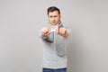 Young man in gray sweater, scarf showing daily pill box on camera on grey background, studio portrait. Healthy