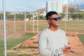 Young man in gray T-shirt and sunglasses typing on cell phone