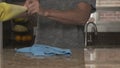 Young man in a gray T-shirt cleaning kitchen granite countertop in his house. He is wearing a bright yellow rubber glove