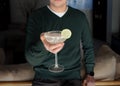 A young man in a green jumper holds a glass with a Margarita cocktail. Gatsby Party. National Margarita Day. Selective focus on a Royalty Free Stock Photo