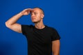 Young man greeting the camera with a military salute in an act of honor and patriotism, showing respect against blue Royalty Free Stock Photo