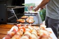 Young man grills some kind of marinated meat and vegetable on gas grill during summer time, food concept