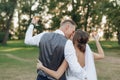 Young man groom kissing hugging young beauteous woman bride, raising hands with glasses of wine. Wedding, celebration.