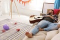 Young man with guitar sleeping on sofa in room after party Royalty Free Stock Photo