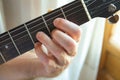 Young man guitarist holding fret board of guitar playing chord by window. Music composing creativity talent performance Royalty Free Stock Photo