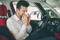 From a young man with handkerchief. Sick guy has runny nose. man makes a cure for the common cold in the car Royalty Free Stock Photo