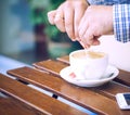 Young man hands holding sugar bag and sweetens coffee in a cafe. Royalty Free Stock Photo