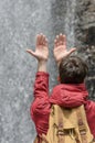 Young man with hands raised towards a waterfall of water