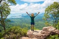 Young man with hands raised up stands on top of rock high in mountains - Concept of success, healthy lifestyle, harmony Royalty Free Stock Photo