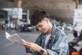 Young man handsome with luggage bag on city street with busy traffic transport looking map, waiting for public bus Royalty Free Stock Photo