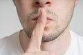 Young man has finger on lips and showing be quiet gesture Royalty Free Stock Photo