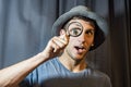 Young man has fun enlarging his eye with a magnifying glass Royalty Free Stock Photo