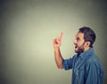 Young man has an idea, pointing with finger up looking up