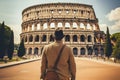 A young man in a hat and a coat looks at the Colosseum in Rome, Italy, Male tourist standing in front of a sandy beach and Royalty Free Stock Photo
