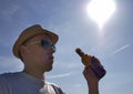 Young man in hat wants to drink refreshing beer from a bottle outdoors Royalty Free Stock Photo