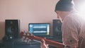 Young man in hat musician composes and records soundtrack playing the guitar using computer, headphones and keyboard Royalty Free Stock Photo