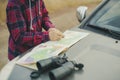 Young man in hat with road map and binoculars searching the correct road f