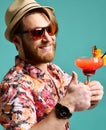 Young man in hat show thumb up drink red margarita cocktail drink juice happy on blue mint Royalty Free Stock Photo