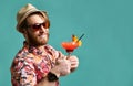 Young man in hat show thumb up drinking red margarita cocktail drink juice happy looking at camera over blue Royalty Free Stock Photo