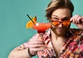 Young man in hat and sunglasses drinking red margarita cocktail drink juice happy looking at camera over blue mint Royalty Free Stock Photo