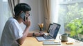 Young man having cell phone conversation and working with computer laptop a home Royalty Free Stock Photo