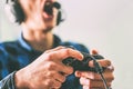 Young man having fun playing video games online using headphones and microphone - Close up male hands gamer holding a joystick