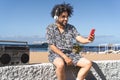 Young man having fun using mobile smartphone while listening music on the beach during summer vacation Royalty Free Stock Photo
