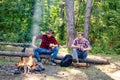 Young man having picnic in woods. Camp adventure and travel concept. Group of two male friends camping with marshmallows Royalty Free Stock Photo