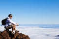 Young Man Having a Rest in a High Peak Over Clouds