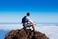 Young Man Having a Rest in a High Peak Over Clouds