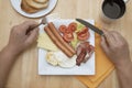 A young man is having a traditional english breakfast with bacon and eggs. Top view. Wooden table. Royalty Free Stock Photo