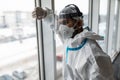 Young man in Hazmat protective suits look glass at home or office during outbreak of Coronavirus, Covid-19