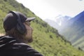 Young man in headphones listening music in nature and at the mountain